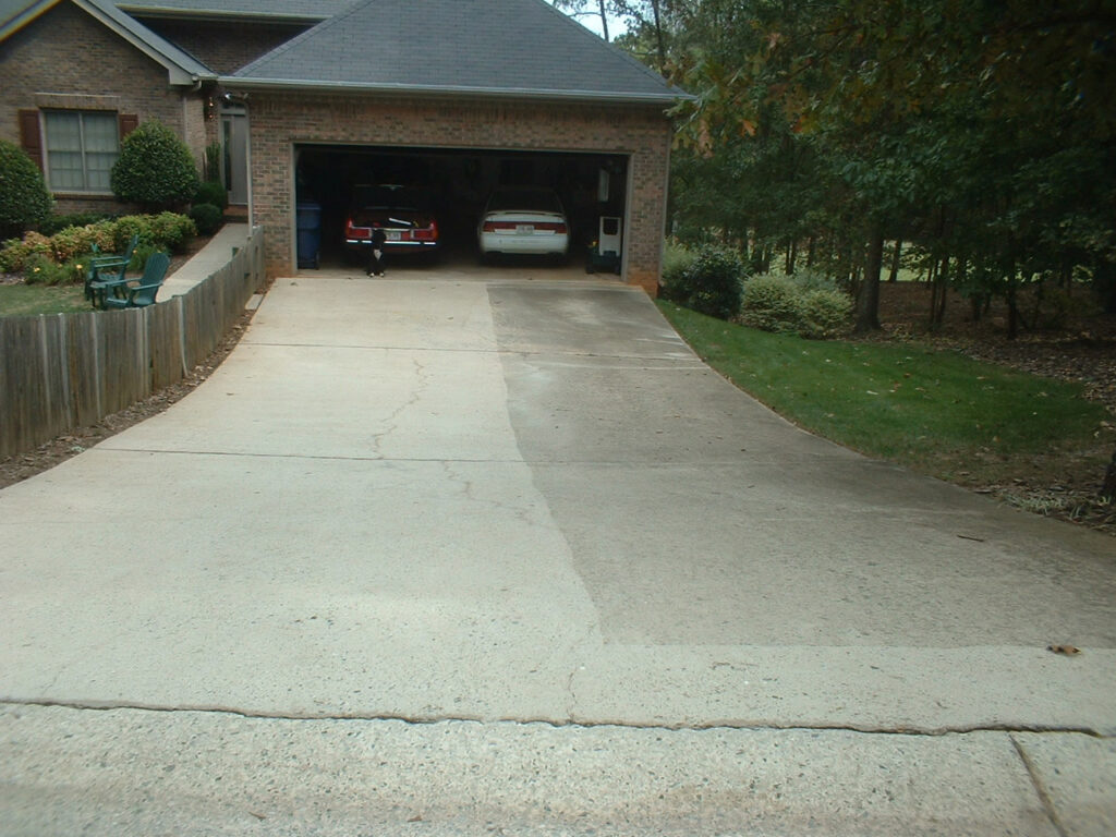 Concrete driveway showing a stark contrast between a cleaned, light-colored side and a dirty, dark-colored side